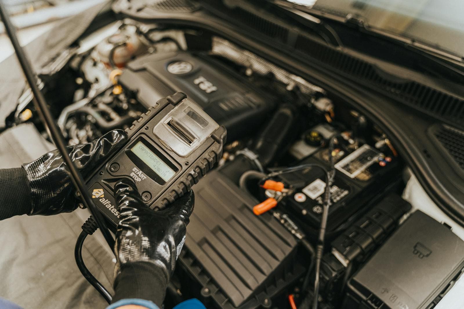 Battery tester connected to a car battery in an open engine bay