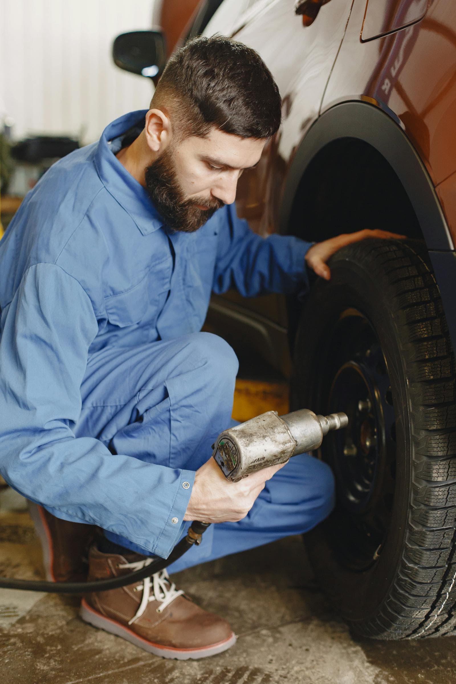 Mechanic loosening wheel nuts with an air impact wrench